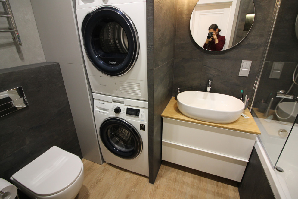 Exempel på ett litet modernt beige beige en-suite badrum, med släta luckor, ett undermonterat badkar, en dusch/badkar-kombination, en vägghängd toalettstol, svart kakel, porslinskakel, grå väggar, klinkergolv i porslin, ett nedsänkt handfat, träbänkskiva, beiget golv och dusch med duschdraperi