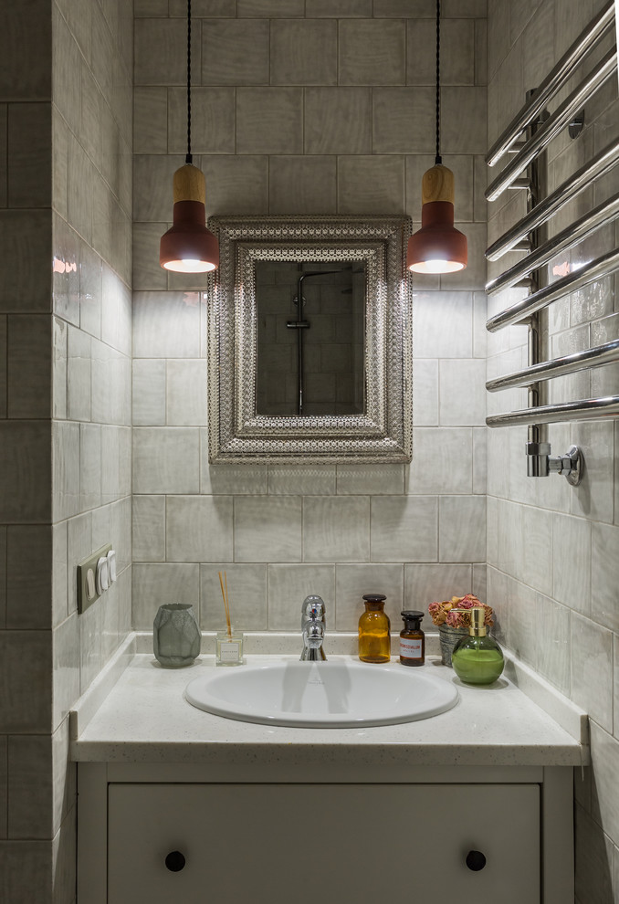 Diseño de cuarto de baño tradicional renovado pequeño con armarios con paneles lisos, puertas de armario blancas, baldosas y/o azulejos grises, baldosas y/o azulejos de cerámica, encimera de acrílico y lavabo encastrado