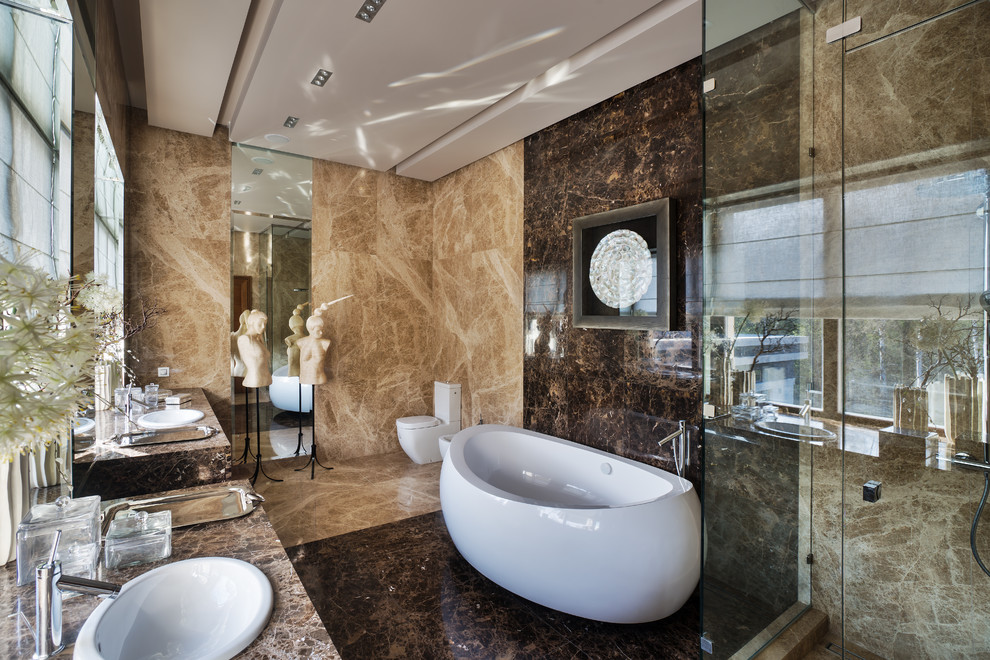 Ispirazione per una stanza da bagno padronale minimal con vasca freestanding, doccia ad angolo, WC a due pezzi, piastrelle beige, piastrelle marroni, lavabo da incasso, top in marmo e pavimento marrone