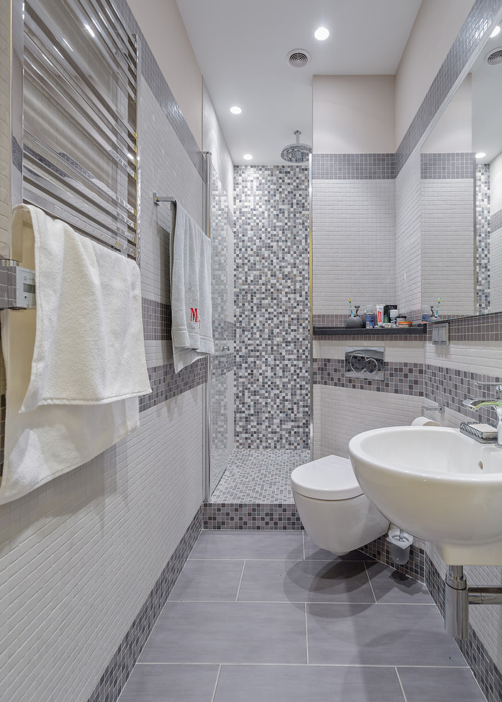 Imagen de cuarto de baño largo y estrecho contemporáneo con ducha empotrada, sanitario de pared, baldosas y/o azulejos blancos, baldosas y/o azulejos grises, paredes multicolor, aseo y ducha, lavabo suspendido y ducha con puerta con bisagras