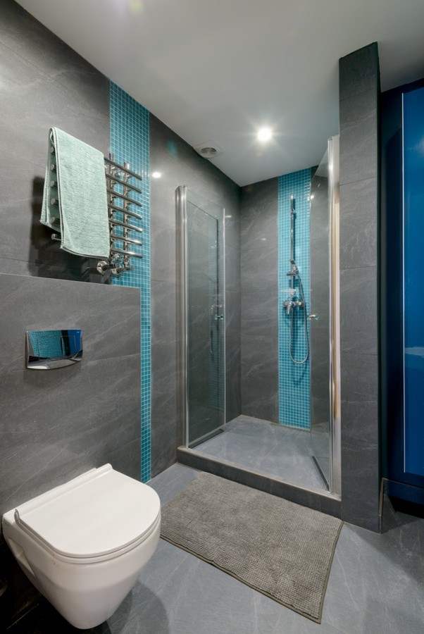 Diseño de cuarto de baño contemporáneo con ducha empotrada, sanitario de pared, baldosas y/o azulejos azules y baldosas y/o azulejos grises