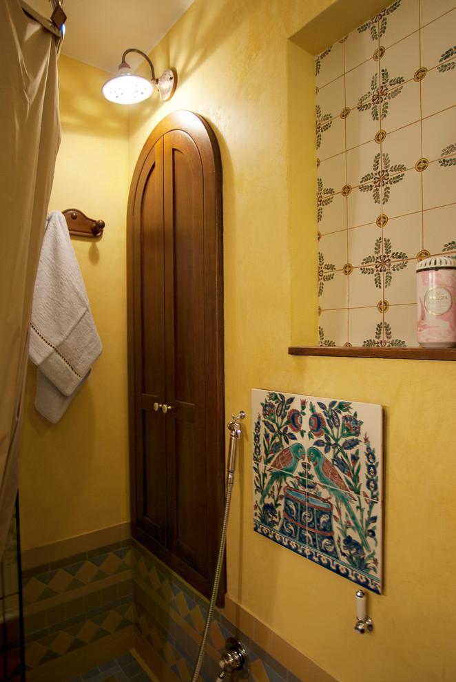 Cette photo montre une salle de bain principale rétro de taille moyenne avec un placard avec porte à panneau encastré, des portes de placard marrons, une baignoire indépendante, une douche ouverte, WC suspendus, un carrelage multicolore, des carreaux de céramique, un mur jaune, un sol en carrelage de céramique, un lavabo intégré, un plan de toilette en stratifié, un sol multicolore, une cabine de douche avec un rideau et un plan de toilette blanc.