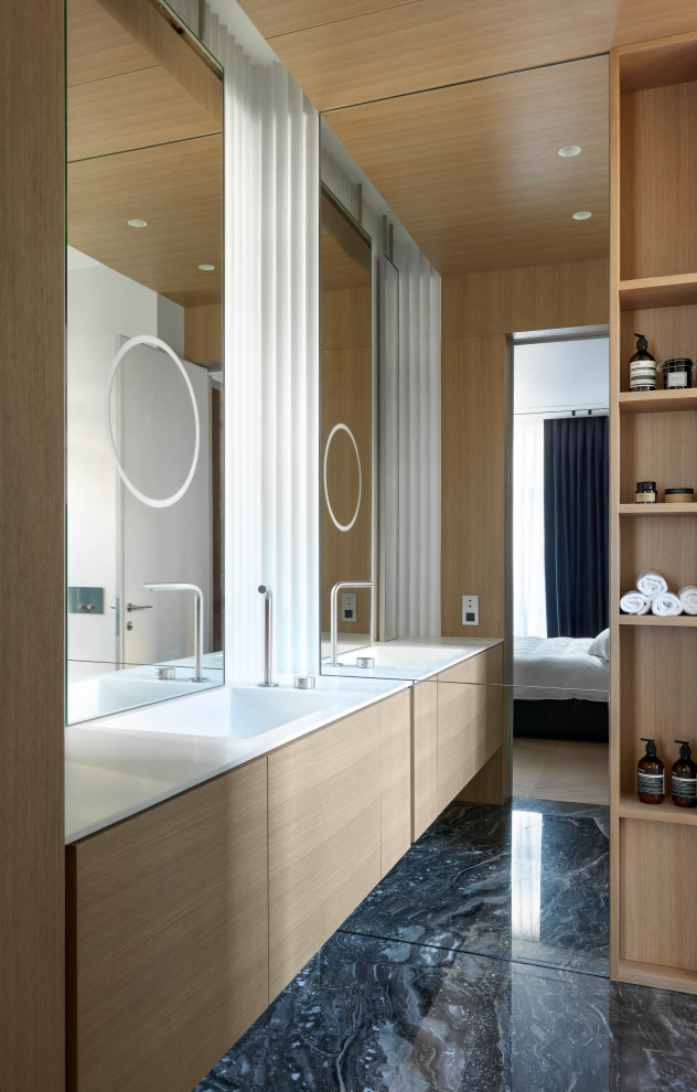 Идея дизайна: ванная комната в современном стиле с плоскими фасадами, светлыми деревянными фасадами, монолитной раковиной, черным полом и белой столешницей