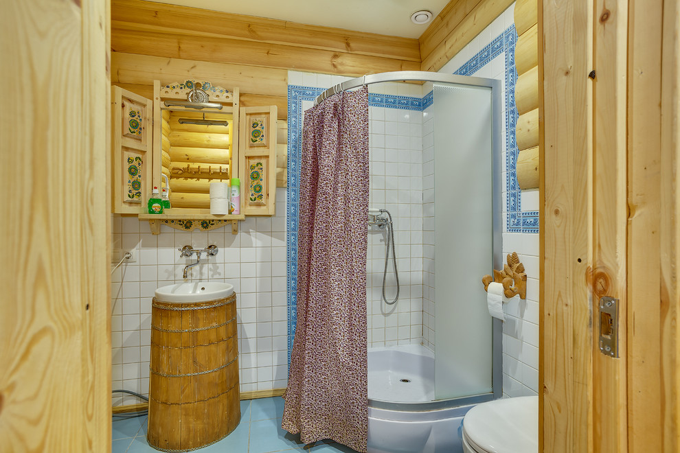 Cette image montre une salle d'eau chalet avec une douche d'angle, un carrelage blanc, un lavabo posé, un sol bleu et une cabine de douche avec un rideau.