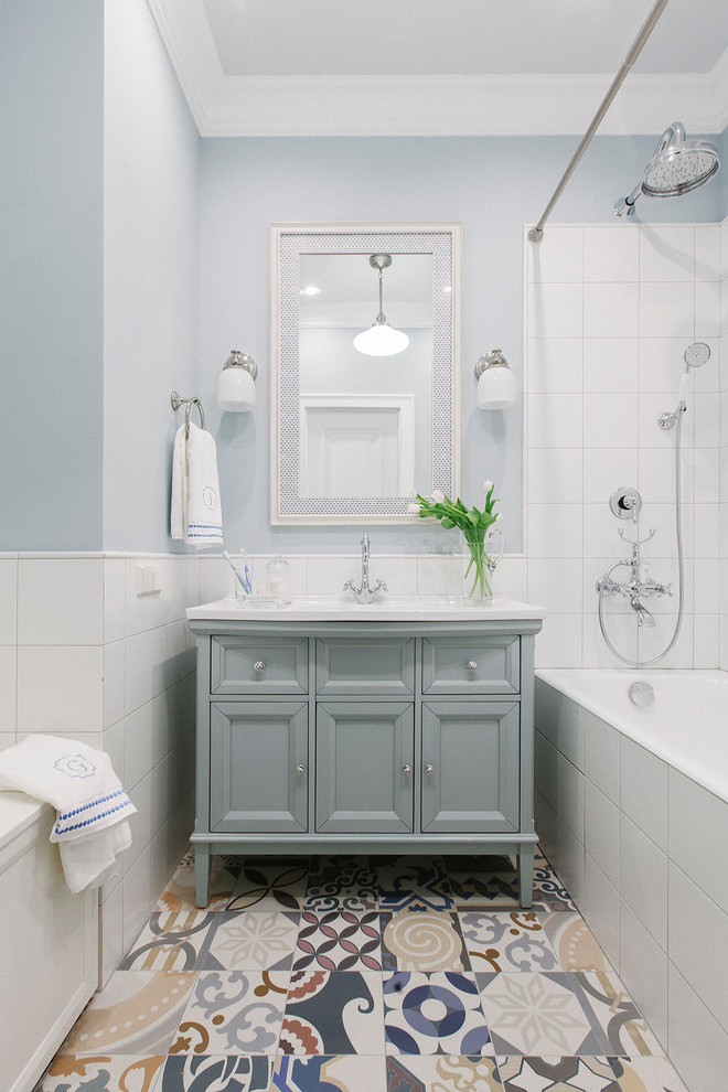 На фото: главная ванная комната в стиле неоклассика (современная классика) с серыми фасадами, белой плиткой, разноцветным полом, шторкой для ванной, накладной ванной, душем над ванной, синими стенами, полом из цементной плитки и фасадами с утопленной филенкой с