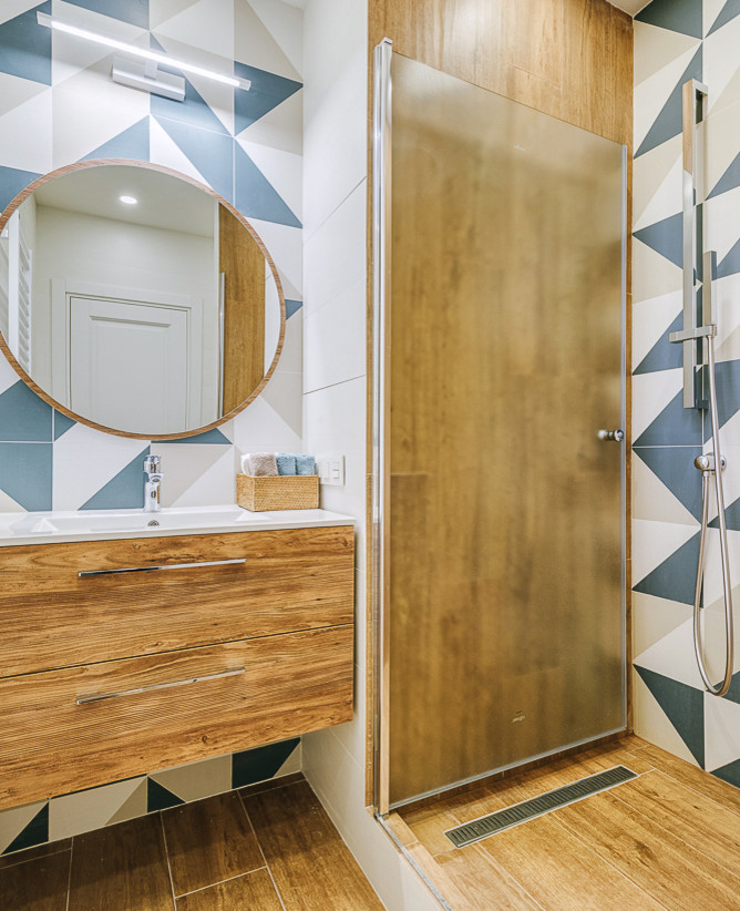 Пример оригинального дизайна: ванная комната в скандинавском стиле с плоскими фасадами, фасадами цвета дерева среднего тона, разноцветной плиткой, душевой кабиной, монолитной раковиной и коричневым полом