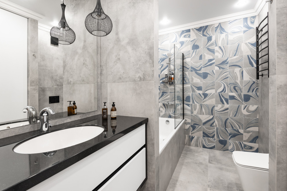 На фото: главная ванная комната в современном стиле с плоскими фасадами, серой плиткой, врезной раковиной и серым полом с