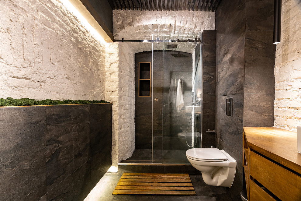 Пример оригинального дизайна: ванная комната в современном стиле с плоскими фасадами, фасадами цвета дерева среднего тона, душем в нише, инсталляцией, белыми стенами, черным полом, душем с раздвижными дверями и коричневой столешницей