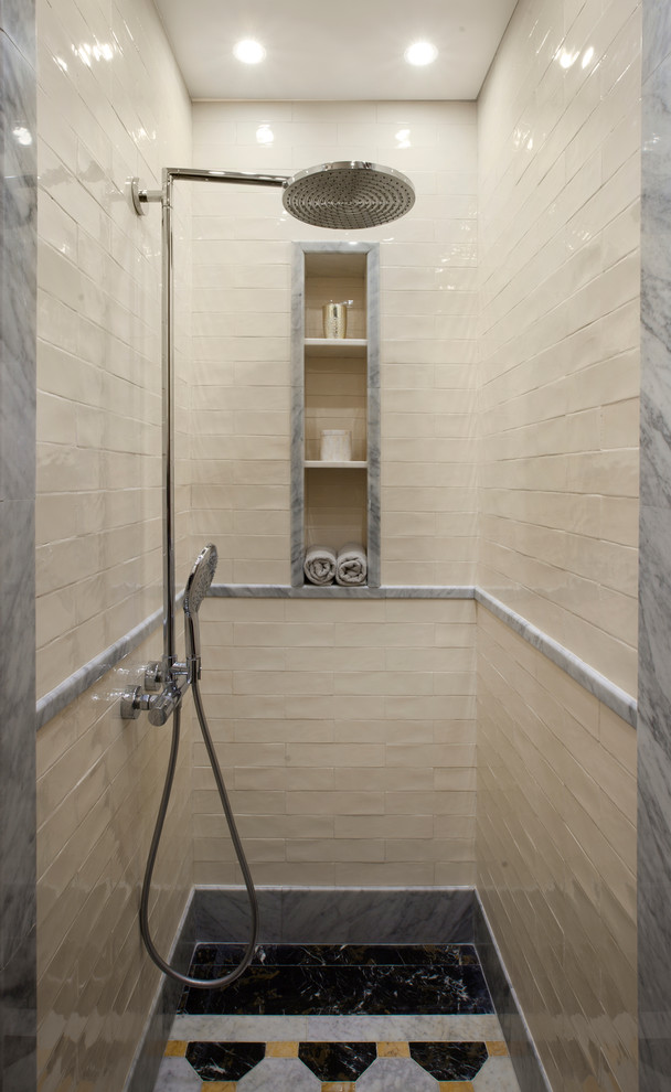 Inredning av ett badrum, med en dusch i en alkov, en vägghängd toalettstol, vit kakel, keramikplattor, vita väggar, ett undermonterad handfat och marmorbänkskiva
