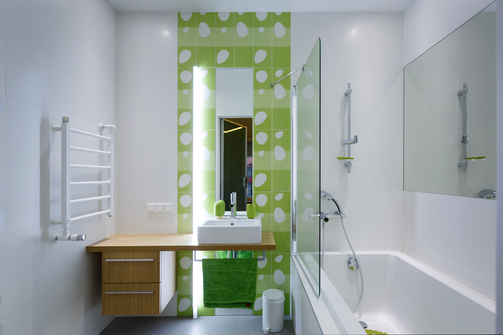 Immagine di una stanza da bagno per bambini design con ante lisce, ante in legno scuro, vasca ad alcova, vasca/doccia, WC sospeso, piastrelle bianche, piastrelle verdi e lavabo a bacinella