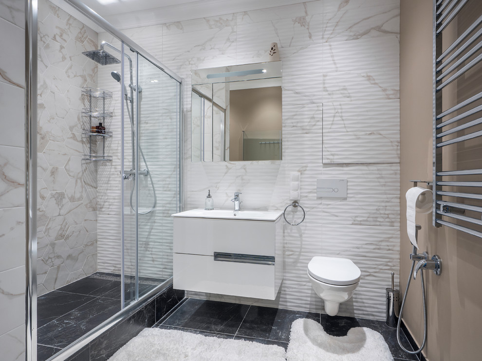На фото: ванная комната в современном стиле с плоскими фасадами, белыми фасадами, душем в нише, инсталляцией, бежевой плиткой, белой плиткой, бежевыми стенами, душевой кабиной, монолитной раковиной, черным полом и душем с раздвижными дверями с