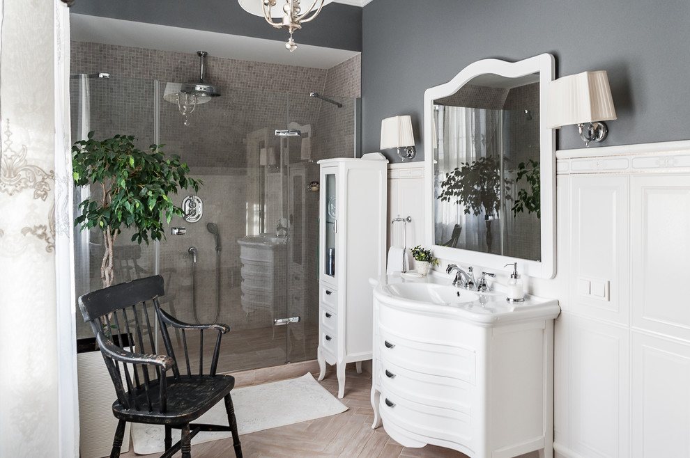 Cette image montre une salle de bain traditionnelle avec un placard avec porte à panneau encastré, des portes de placard blanches, un mur gris, un lavabo intégré, un sol beige et une cabine de douche à porte battante.