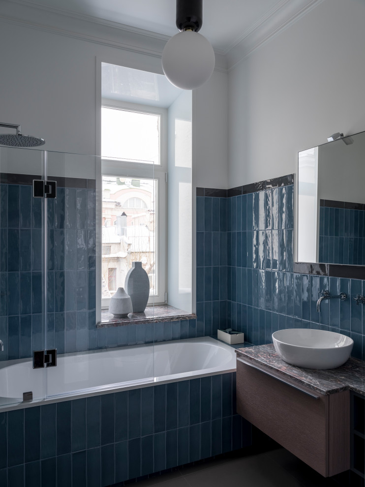 На фото: ванная комната в стиле неоклассика (современная классика) с плоскими фасадами, фасадами цвета дерева среднего тона, накладной ванной, душем над ванной, синей плиткой, белыми стенами, душевой кабиной, настольной раковиной, открытым душем, серой столешницей и фартуком