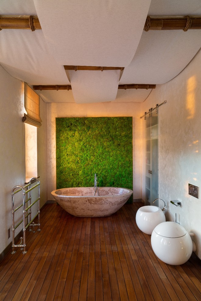 На фото: главная ванная комната в восточном стиле с отдельно стоящей ванной, биде, белыми стенами и паркетным полом среднего тона с