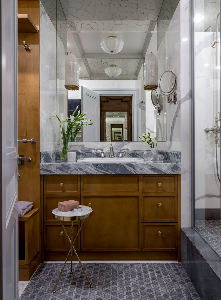 Inredning av ett klassiskt litet grå grått badrum med dusch, med luckor med infälld panel, bruna skåp, en dusch i en alkov, en vägghängd toalettstol, vit kakel, marmorkakel, vita väggar, marmorgolv, ett nedsänkt handfat, marmorbänkskiva, grått golv och med dusch som är öppen