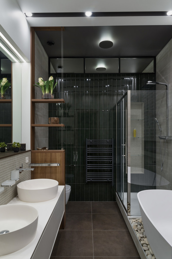 Свежая идея для дизайна: большая главная ванная комната в современном стиле с плоскими фасадами, белыми фасадами, отдельно стоящей ванной, угловым душем, инсталляцией, керамической плиткой, полом из керамогранита, настольной раковиной, столешницей из искусственного кварца, коричневым полом, душем с раздвижными дверями, черной плиткой, серой плиткой и белыми стенами - отличное фото интерьера