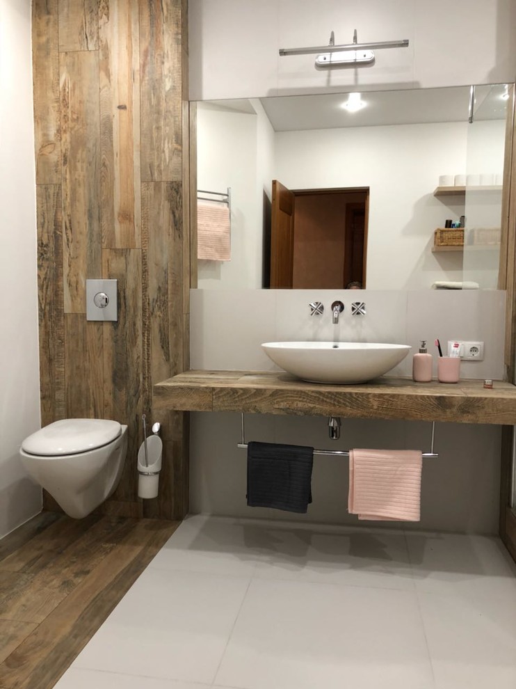 Ispirazione per una stanza da bagno minimal di medie dimensioni con WC sospeso, piastrelle grigie, pareti grigie, lavabo a bacinella, top in legno e pavimento grigio
