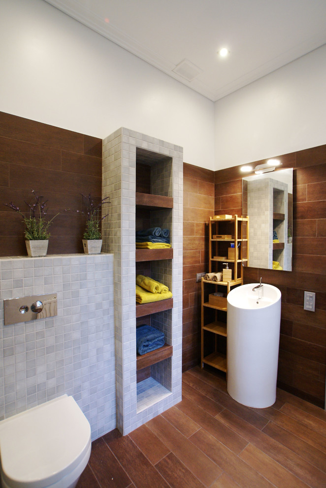 Imagen de cuarto de baño actual con sanitario de pared, baldosas y/o azulejos grises y lavabo con pedestal