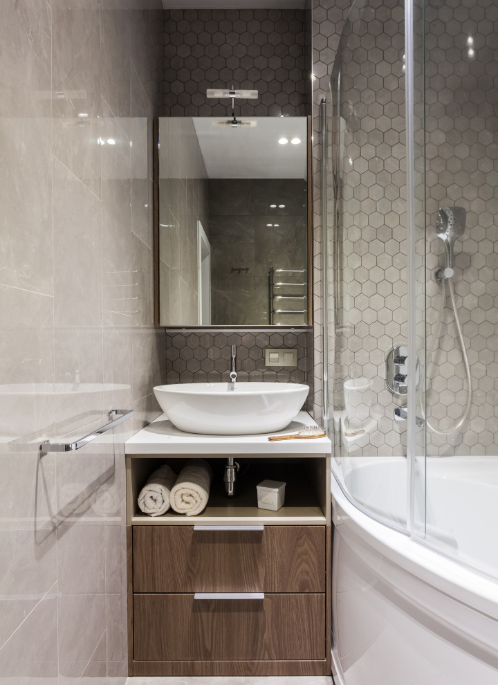 Cette photo montre une petite salle d'eau tendance en bois brun avec un placard à porte plane, une douche d'angle, un carrelage gris, une vasque, un sol gris, une cabine de douche à porte battante, un plan de toilette blanc et meuble-lavabo encastré.