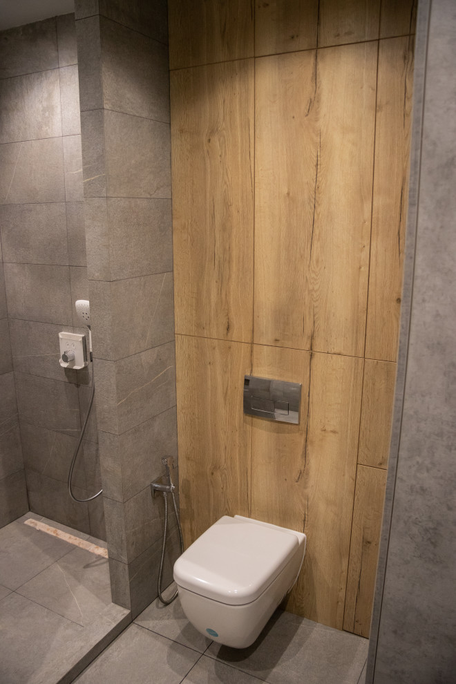 Modern inredning av ett mellanstort vit vitt badrum med dusch, med släta luckor, skåp i slitet trä, våtrum, en vägghängd toalettstol, grå kakel, porslinskakel, grå väggar, klinkergolv i porslin, ett integrerad handfat, bänkskiva i akrylsten, grått golv och med dusch som är öppen