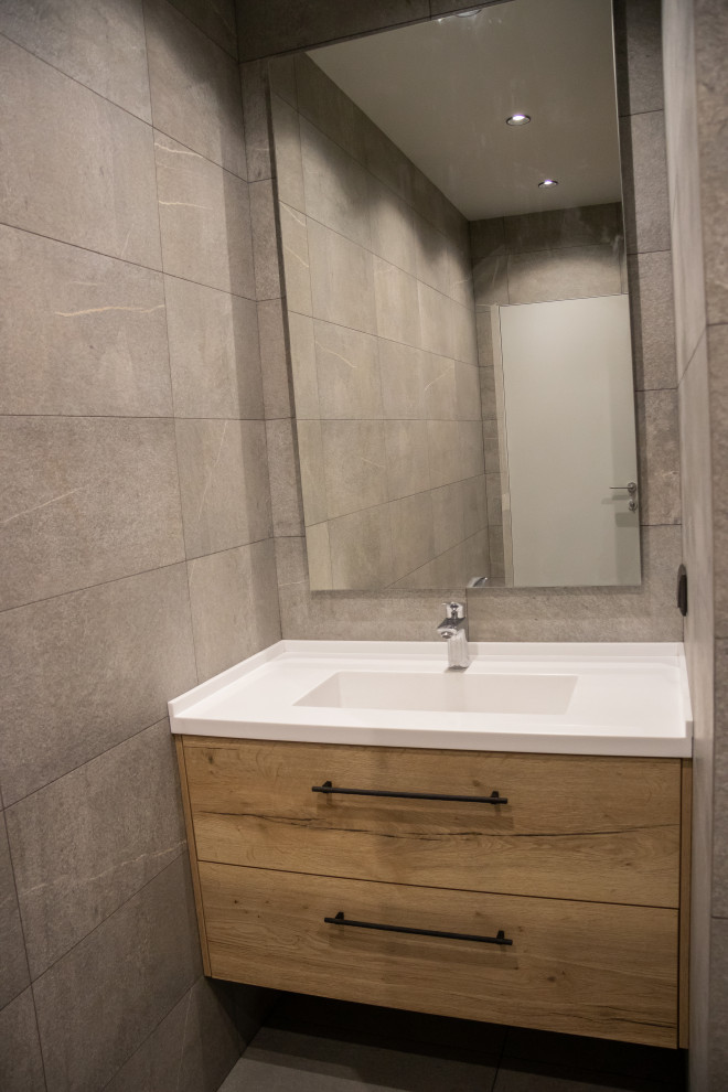 Inspiration för mellanstora moderna vitt badrum med dusch, med släta luckor, skåp i slitet trä, våtrum, en vägghängd toalettstol, grå kakel, porslinskakel, grå väggar, klinkergolv i porslin, ett integrerad handfat, bänkskiva i akrylsten, grått golv och med dusch som är öppen