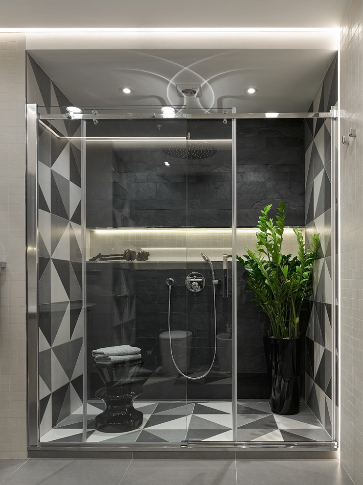 Cette image montre une grande salle de bain design avec un carrelage gris, un carrelage noir, des carreaux de porcelaine, un sol en carrelage de porcelaine, un mur noir et une cabine de douche à porte coulissante.