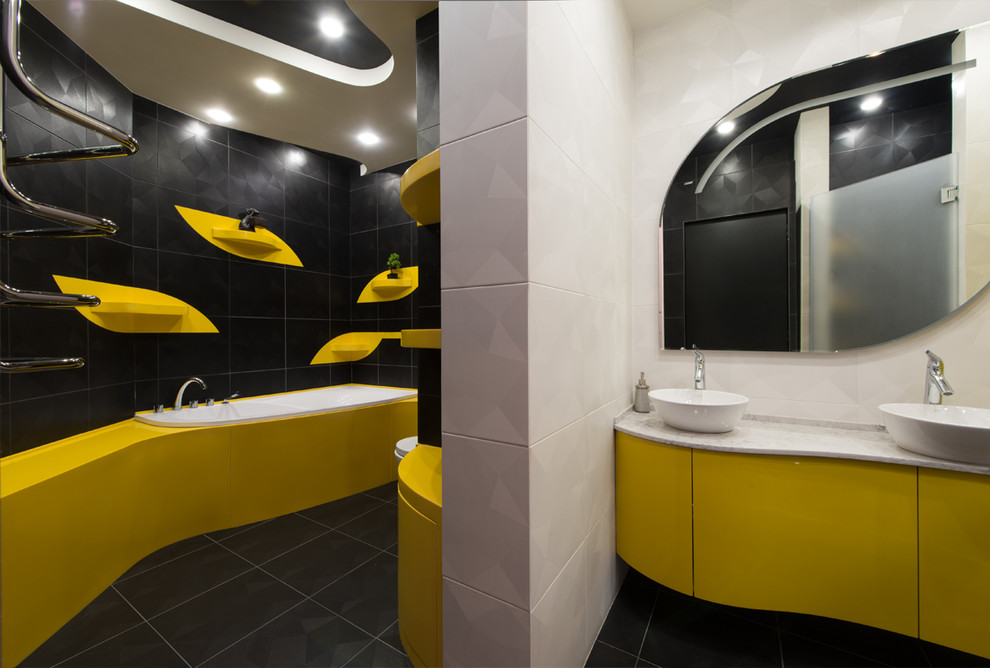 Свежая идея для дизайна: большая главная ванная комната в современном стиле с плоскими фасадами, желтыми фасадами, полновстраиваемой ванной, душевой комнатой, инсталляцией, черно-белой плиткой, керамической плиткой, черными стенами, полом из керамической плитки, настольной раковиной, столешницей из искусственного кварца, черным полом, душем с распашными дверями и белой столешницей - отличное фото интерьера