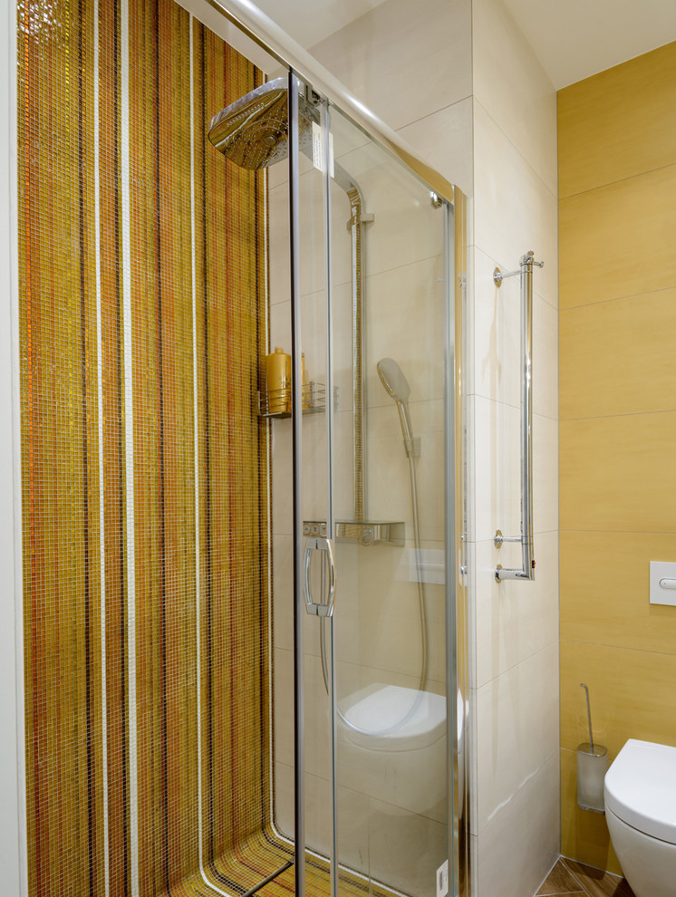 Inspiration för ett funkis badrum, med en vägghängd toalettstol, bänkskiva i akrylsten, dusch med skjutdörr, gul kakel, mosaik, gula väggar och brunt golv