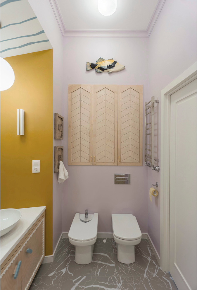 Eklektisches Badezimmer mit Urinal, lila Wandfarbe, Aufsatzwaschbecken, grauem Boden, weißer Waschtischplatte, flächenbündigen Schrankfronten und hellen Holzschränken in Moskau