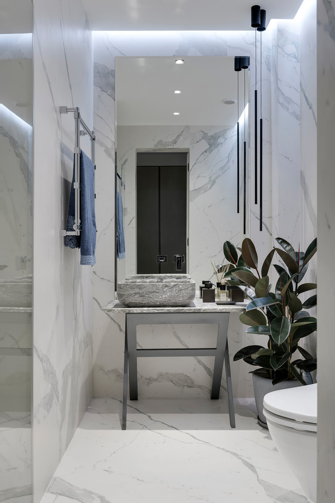 Cette image montre une salle de bain design avec un carrelage blanc, un sol blanc et un plan de toilette gris.