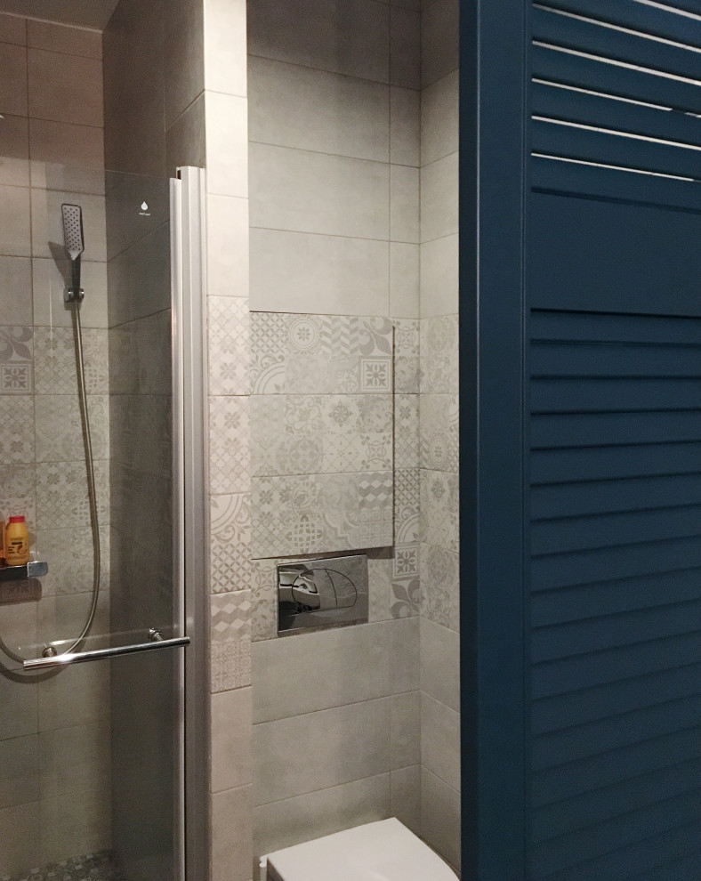 Свежая идея для дизайна: ванная комната среднего размера в скандинавском стиле с фасадами с филенкой типа жалюзи, синими фасадами, душем в нише, раздельным унитазом, серой плиткой, керамической плиткой, серыми стенами, полом из керамической плитки, душевой кабиной, серым полом и душем с распашными дверями - отличное фото интерьера