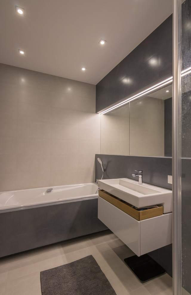 Inspiration for a large contemporary ensuite bathroom in Other with flat-panel cabinets, white cabinets, a built-in bath, grey tiles, porcelain tiles, grey walls, porcelain flooring, a built-in sink and solid surface worktops.