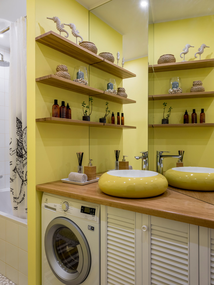 Exempel på ett litet modernt beige beige en-suite badrum, med luckor med lamellpanel, vita skåp, ett badkar i en alkov, gula väggar, klinkergolv i småsten, ett nedsänkt handfat, träbänkskiva och vitt golv