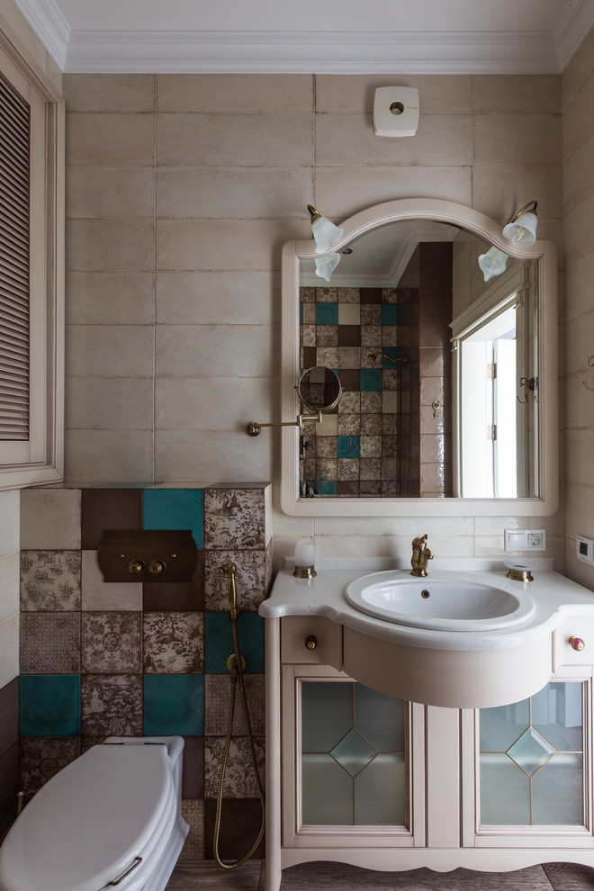 Klassisches Badezimmer mit beigen Fliesen, Einbauwaschbecken und Wandtoilette mit Spülkasten in Sonstige