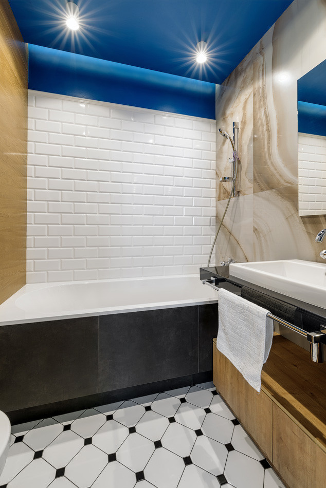 На фото: главная ванная комната в стиле неоклассика (современная классика) с ванной в нише, душем над ванной, белой плиткой, плиткой кабанчик, накладной раковиной и черной столешницей