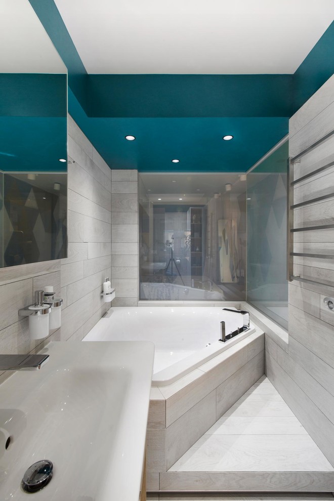 На фото: главная ванная комната в современном стиле с угловой ванной, синими стенами и серым полом с