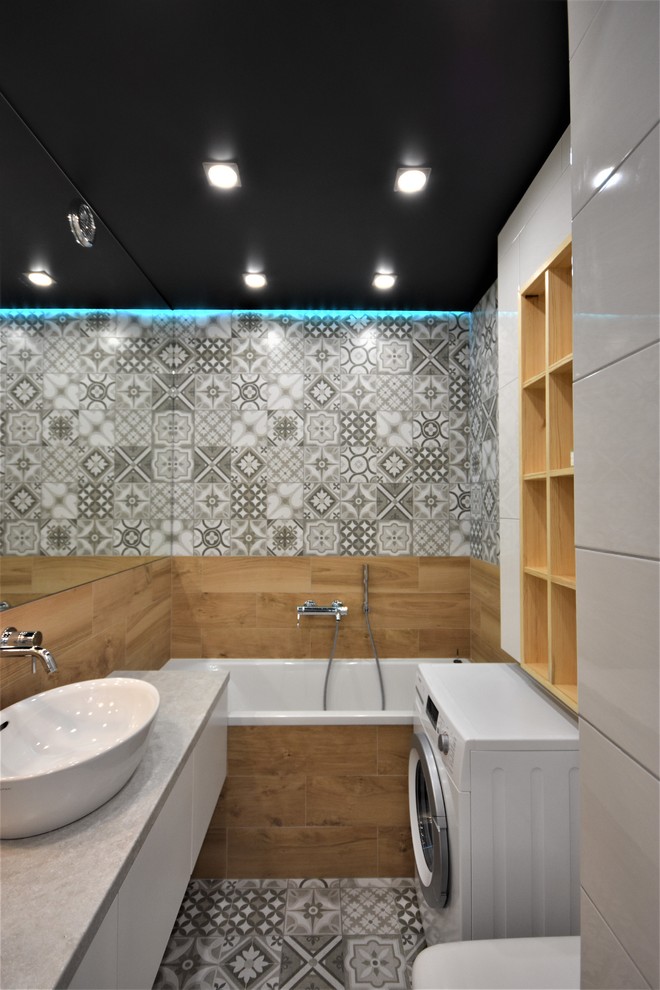 Idéer för att renovera ett litet industriellt en-suite badrum, med släta luckor, vita skåp, ett undermonterat badkar, en dusch/badkar-kombination, en vägghängd toalettstol, svart och vit kakel, porslinskakel, vita väggar, klinkergolv i porslin, ett nedsänkt handfat, bänkskiva i betong, grått golv och med dusch som är öppen