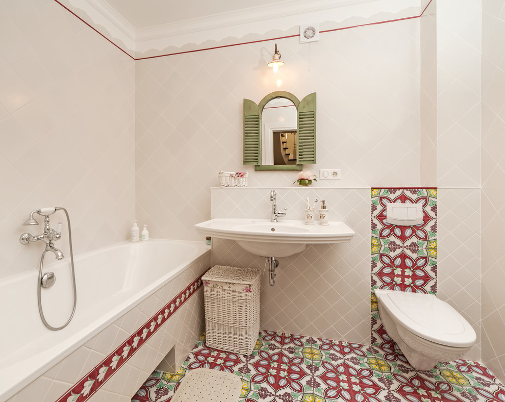 Diseño de cuarto de baño principal mediterráneo con bañera empotrada, combinación de ducha y bañera, sanitario de pared, baldosas y/o azulejos beige, baldosas y/o azulejos multicolor y lavabo suspendido