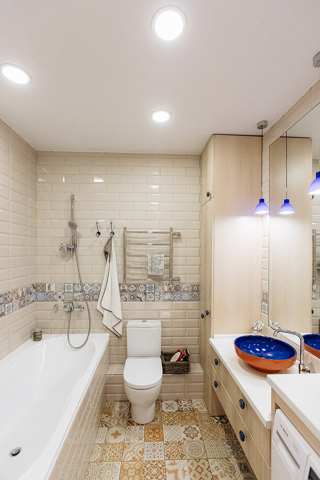 Diseño de cuarto de baño principal tradicional con armarios con paneles lisos, puertas de armario de madera clara, bañera encastrada, combinación de ducha y bañera, sanitario de dos piezas, baldosas y/o azulejos beige, baldosas y/o azulejos multicolor, lavabo sobreencimera y ducha abierta