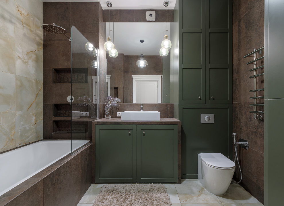 На фото: ванная комната в стиле неоклассика (современная классика) с зелеными фасадами, ванной в нише, душем над ванной, коричневой плиткой, настольной раковиной, бежевым полом, коричневой столешницей, фасадами в стиле шейкер и унитазом-моноблоком с