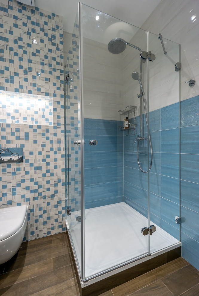 Idee per una stanza da bagno design di medie dimensioni con WC sospeso, piastrelle blu, piastrelle bianche, piastrelle in ceramica, pavimento in gres porcellanato e doccia ad angolo