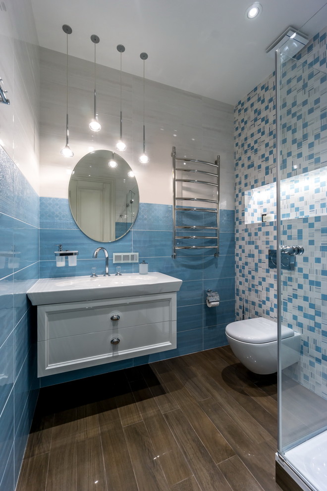 Diseño de cuarto de baño contemporáneo de tamaño medio con sanitario de pared, baldosas y/o azulejos azules, baldosas y/o azulejos blancos, baldosas y/o azulejos de cerámica, suelo de baldosas de porcelana, armarios con paneles empotrados, puertas de armario blancas, lavabo tipo consola y espejo con luz