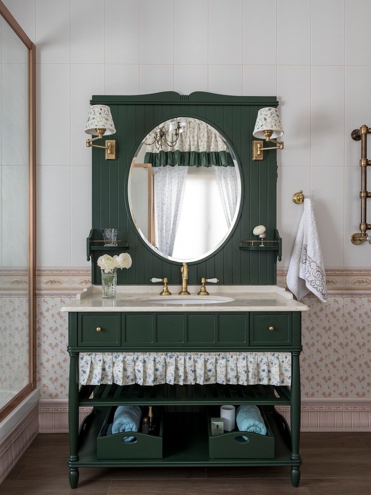 Lantlig inredning av ett beige beige badrum, med gröna skåp, beige kakel, keramikplattor, klinkergolv i porslin, ett undermonterad handfat, marmorbänkskiva, brunt golv och luckor med infälld panel