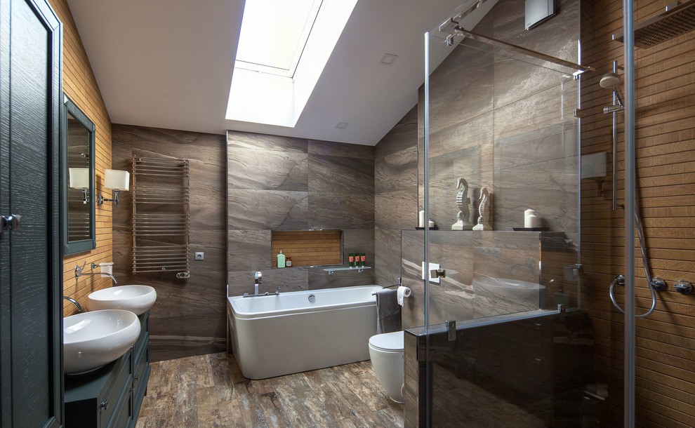 Пример оригинального дизайна: большая главная ванная комната в современном стиле с серыми фасадами, керамогранитной плиткой, полом из керамогранита, столешницей из дерева, душем с распашными дверями, фасадами с утопленной филенкой, раздельным унитазом, серой плиткой, настольной раковиной и коричневым полом