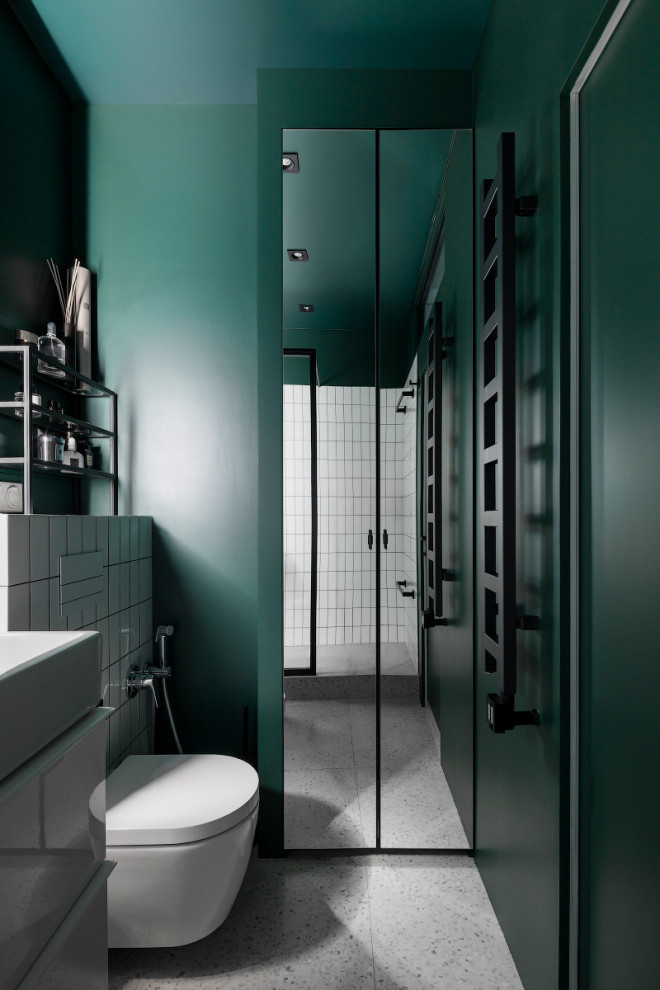 Exemple d'une salle de bain tendance avec un placard à porte plane, des portes de placard blanches, WC suspendus, un mur vert, un sol en terrazzo, un sol gris et meuble simple vasque.