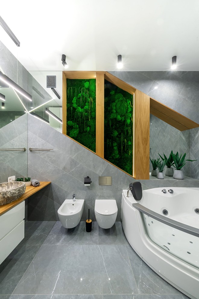 Стильный дизайн: ванная комната в современном стиле с фасадами цвета дерева среднего тона, гидромассажной ванной, серой плиткой, серыми стенами, полом из керамической плитки, столешницей из дерева, серым полом и желтой столешницей - последний тренд