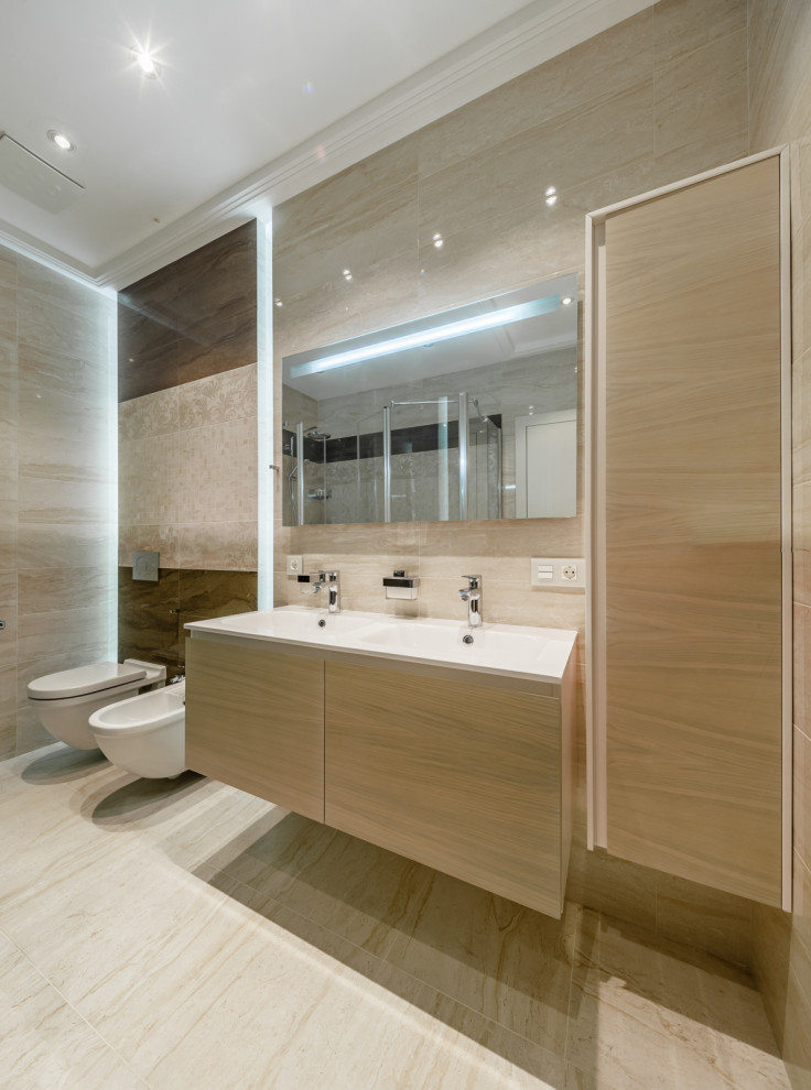 На фото: большая ванная комната в современном стиле с плоскими фасадами, светлыми деревянными фасадами, инсталляцией, бежевой плиткой, монолитной раковиной, бежевым полом и белой столешницей с