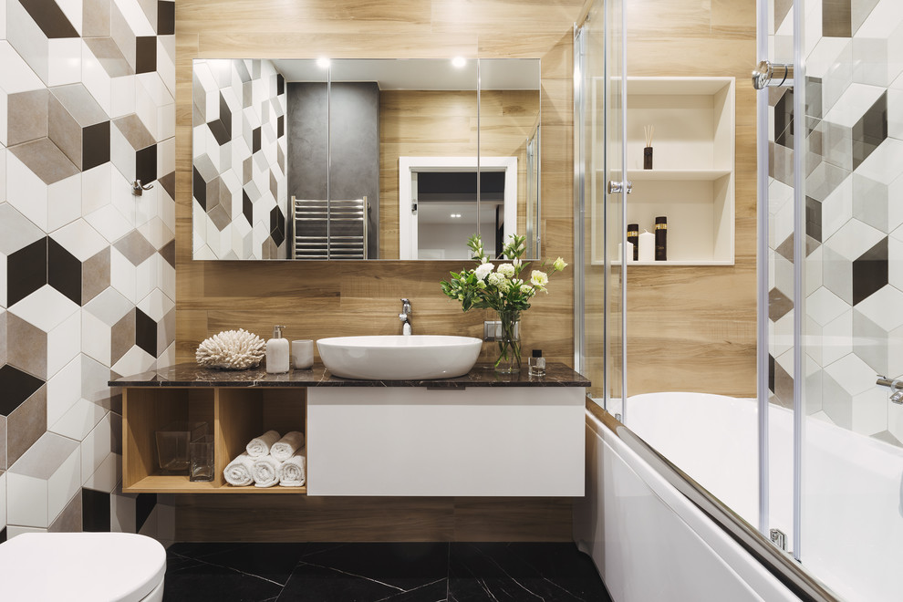 На фото: главная ванная комната в белых тонах с отделкой деревом в современном стиле с плоскими фасадами, белыми фасадами, душем над ванной, разноцветной плиткой, настольной раковиной, черным полом, душем с раздвижными дверями и черной столешницей