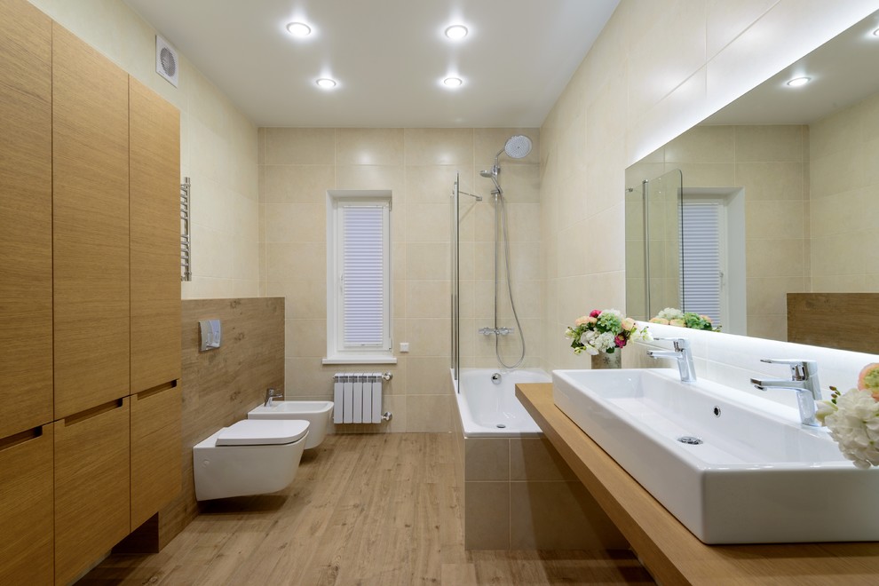 Пример оригинального дизайна: главная ванная комната среднего размера в современном стиле с накладной ванной, душем в нише, биде, паркетным полом среднего тона, врезной раковиной, столешницей из ламината, фасадами цвета дерева среднего тона и открытым душем