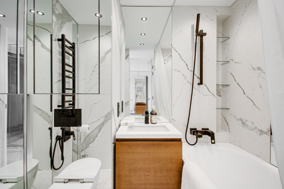 Inredning av ett modernt stort vit vitt en-suite badrum, med en dusch/badkar-kombination, en vägghängd toalettstol, vit kakel, marmorkakel, marmorgolv, dusch med duschdraperi, skåp i mellenmörkt trä, ett badkar i en alkov och ett undermonterad handfat